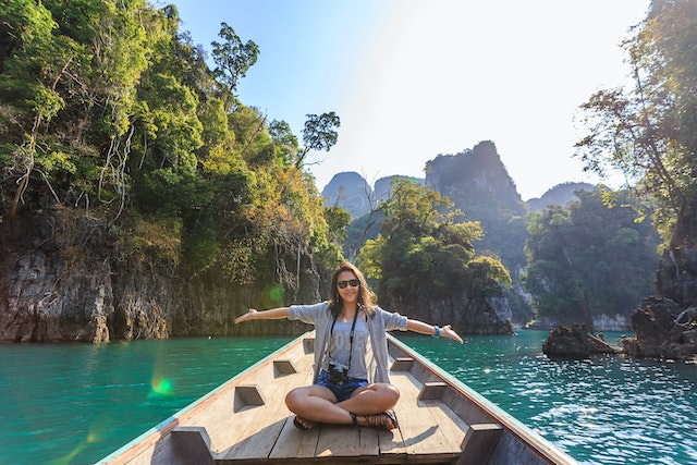 A woman sitting in a small boat at water, smiling and spreading her arms. Behind her are trees and mountains.
(There are plenty of beautiful rivers and lakes to visit during a vacation in Serbia!)